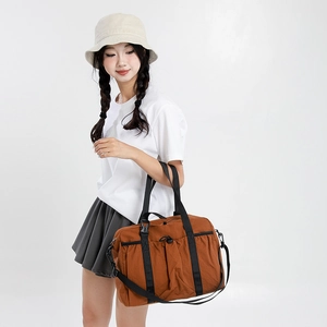 Detailed shot of brown nylon travel tote with drawstrings and straps on model
