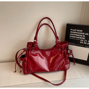 Détail d'un sac cabas en cuir verni rouge brillant avec cordons et doubles poignées