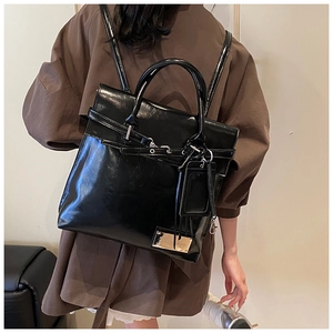 Détail d'un sac à dos en cuir verni noir avec poignée supérieure et boucle en métal chic
