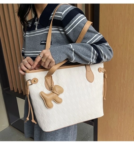 Close-up of large quilted tote bag in beige and tan featuring a cute dog charm detail