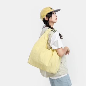 Lifestyle shot of large yellow casual tote bag shown on model against a white background