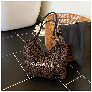 Close-up of leopard print tote bag with white script text in a lifestyle home setting
