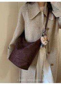 Detail of minimalist dark brown suede tote bag featuring a cute gray bear charm decoration
