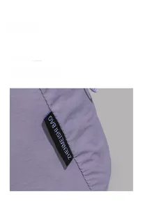 Detail shot of the woven black label and stitching on a light purple tote bag
