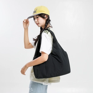 Side view of a large black nylon tote bag on shoulder showing its spacious capacity
