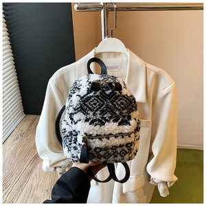 Detail eines Mini-Plüschrucksacks mit schwarz-weißem Wollmuster und Schleifenakzenten