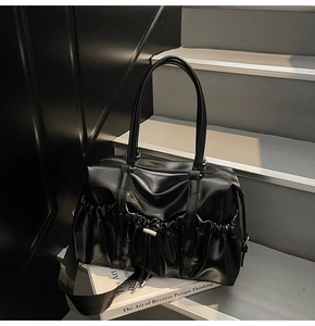 Détail d'un sac cabas en cuir PU noir brillant avec texture plissée et cordon