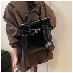 Détail du sac à dos en cuir noir brillant avec boucle décorative et étiquette élégante