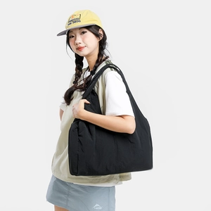Close-up of a large black nylon tote bag with textured surface shown on a female model