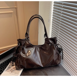 Détails du sac en cuir marron foncé brillant montrant les plis du cordon et les ferrures