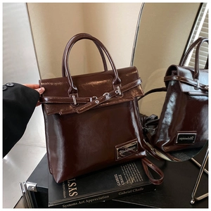 Gros plan détaillé du sac en cuir marron chocolat brillant sur un livre d'art avec miroir