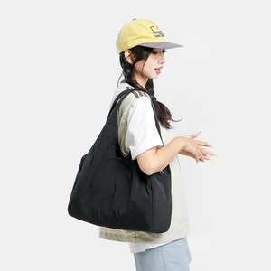 Detailed view of black quilted tote bag with wide strap on model for oversized styling