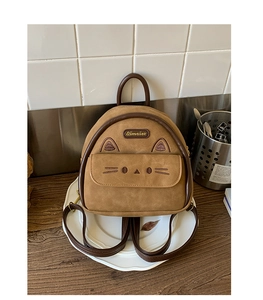 Detail showing the cat ear design and cat face embroidery on a camel brown backpack