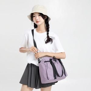 Detailed shot of a purple travel tote bag with black adjustable strap on female model