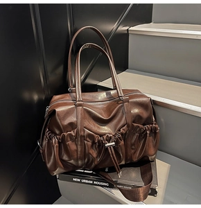 Détail du sac Boston en cuir marron vintage avec plis latéraux sur un livre