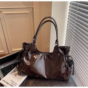 Détail du sac cabas en cuir marron brillant avec cordon latéral et oeillets en métal