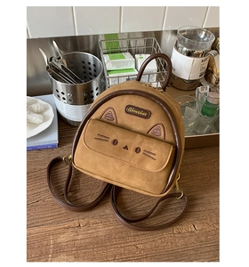 Detail of brown cat-themed mini backpack with cute ear embroidery and brand plaque