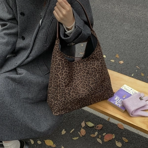 Detailopname van de tote bag met luipaardprint en leren riem in een herfstige setting