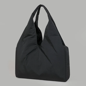 Macro view of the large capacity black nylon tote bag with pleated texture and V-shaped handle