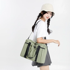 Detail of olive green nylon travel tote bag showing drawstring pocket and buckle strap