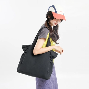 Detail of black nylon tote bag with side drawstring and adjustable wide shoulder strap