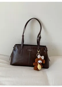 Close-up of brown shoulder bag with sleek PU leather and cute puppy charm detail