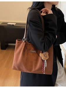 Brown suede tote bag with leather straps and bear charm shown in a crossbody style