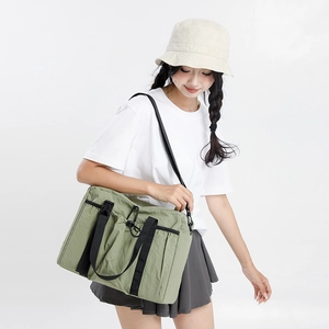 Outdoor look showing adjustable strap and drawstring pocket on green nylon tote bag