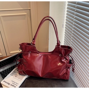 Détail du sac cabas en cuir verni bordeaux avec cordons de serrage et bandoulière réglable