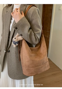 Close-up of large brown suede bucket bag with cute teddy bear charm for daily commute