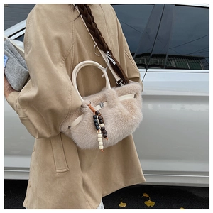 Nahaufnahme der beigen Plüschhandtasche mit Ledergriffen und Perlenquasten-Detail
