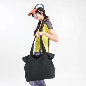 Close-up of black nylon tote bag with drawstring side detail and long shoulder straps