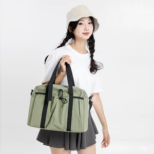 Detail showing the large green nylon travel tote bag with black webbing handles and drawstrings