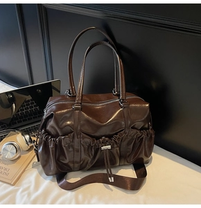 Sac fourre-tout vintage marron avec ordinateur et casque sur un bureau blanc