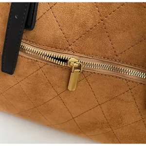 Détail du sac à main en daim marron matelassé avec fermeture éclair dorée et sangle