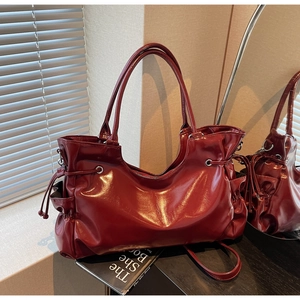 Détail du sac cabas rouge foncé brillant avec poches latérales à cordon et doubles poignées
