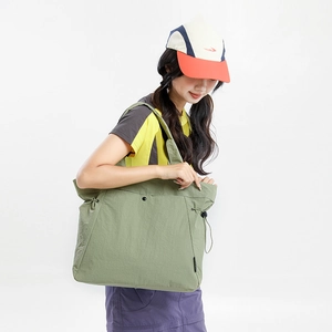 Detail view of olive green nylon tote bag featuring side drawstrings and snap closure