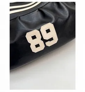 Dettaglio dello zaino nero con strisce bianche e grande toppa con il numero 89