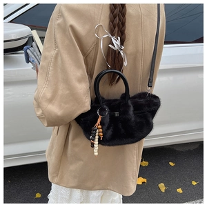 Detail der schwarzen Pelz-Handtasche mit runden Griffen und elegantem Perlenanhänger
