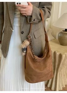 Brown suede shoulder bag shown on model with minimalist retro vibe and plush charm detail