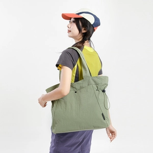 Close-up of grass green nylon tote bag featuring wrinkled texture and drawstring detail