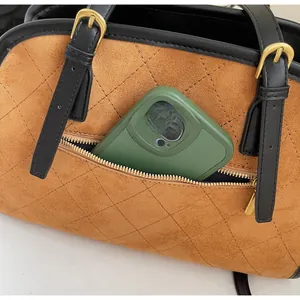 Détail du sac à main en daim marron matelassé avec poche zippée pour ranger un téléphone