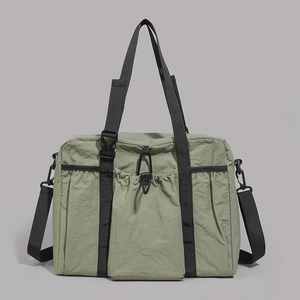 Macro detail of olive green nylon tote bag featuring drawstring pocket and black straps
