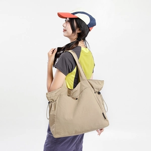 Detail of khaki nylon tote bag with side drawstring pocket and wide shoulder strap