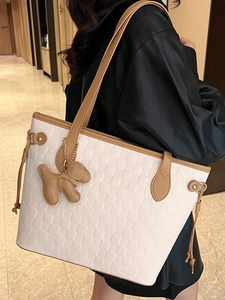 White woven tote bag with brown leather straps and puppy charm shown on shoulder