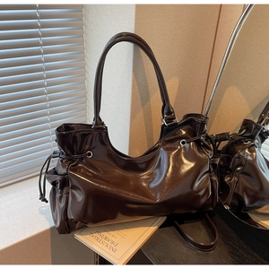 Détail du sac fourre-tout marron brillant avec œillets métalliques et bandoulière réglable