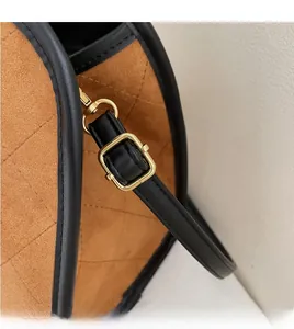 Détail du sac en daim marron avec bordure en cuir noir et boucle dorée réglable de près