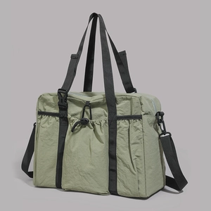 Detail view of large olive green nylon tote bag featuring drawstring pockets and buckles