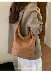Close-up of brown suede oversized tote bag styled with a wool coat for autumn