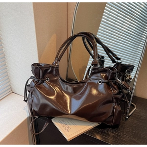 Détails d'un sac à main marron chocolat brillant en similicuir avec cordons latéraux